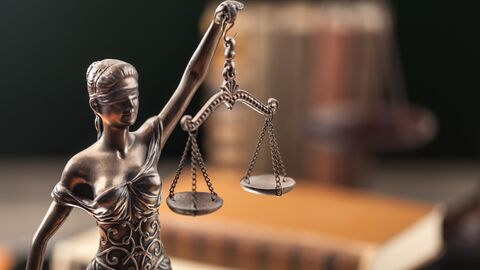 Justitia-Statue vor einem Bücherstapel Justitia-Statue vor einem Bücherstapel