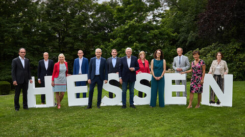 Das hessische Kabinett steht um hüfthohe weiße Buchstaben herum verteilt, die das Wort Hessen bilden