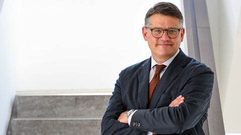 Boris Rhein steht mit verschränkten Armen auf einer Treppe.