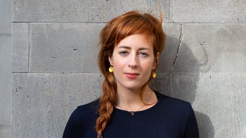 Leona Stahlmann lehnt an einer Steinmauer und schaut in die Kamera