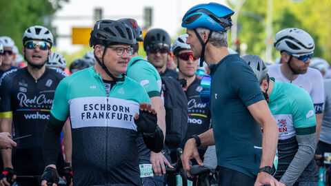 Ministerpräsident Rhein in Radsport-Kleidung neben weiteren Teilnehmern des Radrennens.