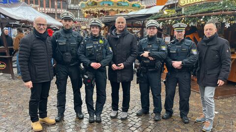 Landespolizeipräsident Robert Schäfer, Innenminister Roman Poseck und Frankfurts Polizeipräsident Stefan Müller gemeinsam mit Polizeibeamten der Weihnachtsmarktwache