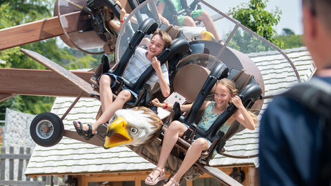 Kinder sitzen in einem Fahrgeschäft und lachen.