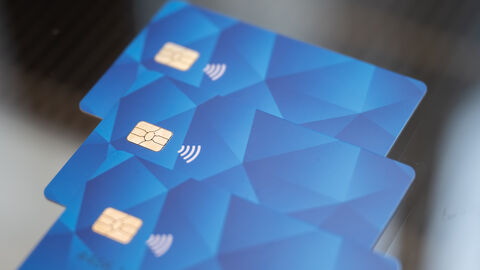 Drei blaue Geldkarten liegen übereinander auf einem Glastisch.